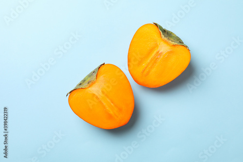 Fresh ripe persimmon halves on blue background