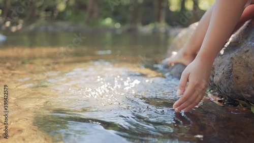 Hand of woman touching water in the waterfall or river lake vacation travel