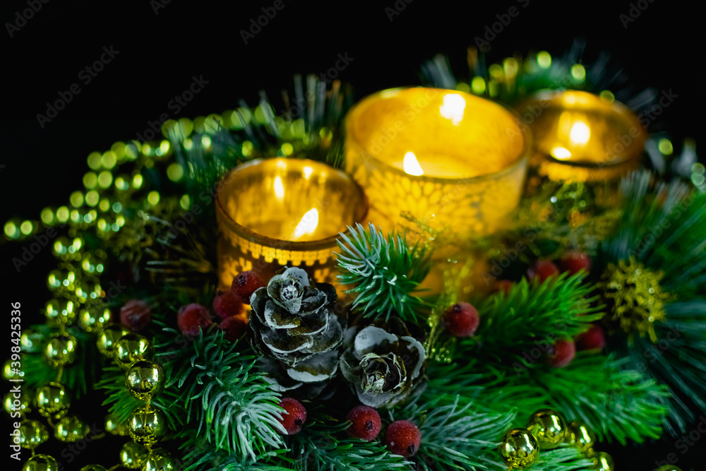 Christmas decorations on a black background by candlelight. Composition of Golden balls and beads, openwork candlesticks with patterns and branches of the Christmas tree. Elegant cones and red berries