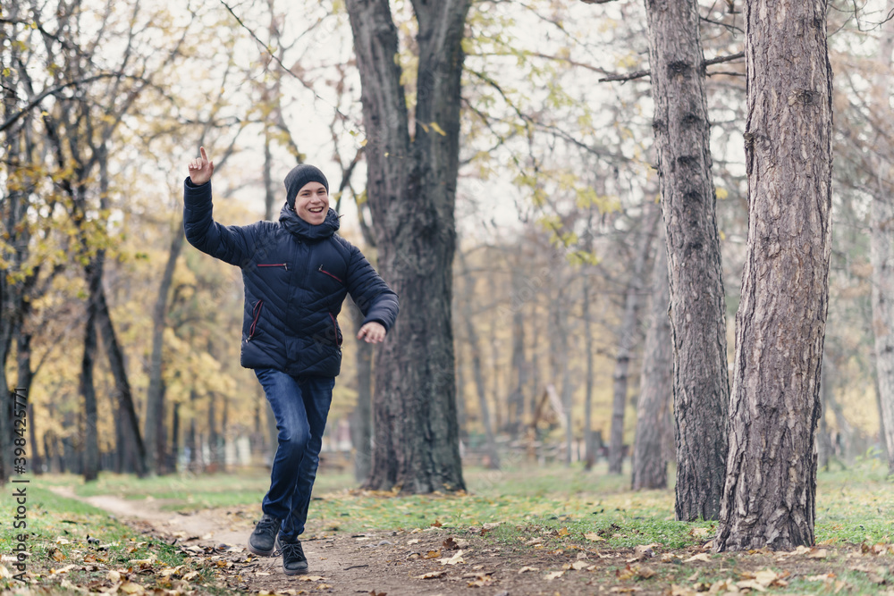 a boy running through the park and enjoys autumn, beautiful nature with yellow leaves