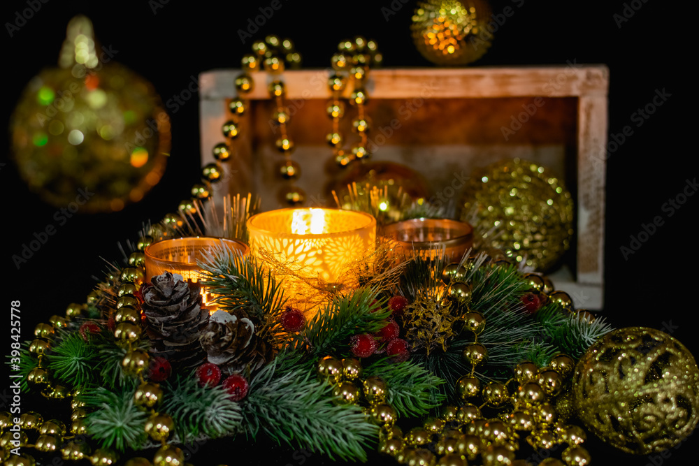 Christmas decorations on a black background by candlelight. Composition of Golden balls and beads, openwork candlesticks with patterns and branches of the Christmas tree. Elegant cones and red berries