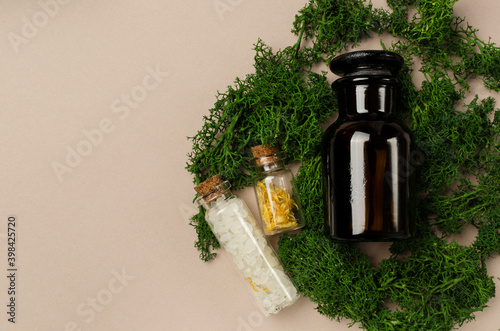 Top view of bottles of beauty ingregients on thegreen plant, bright brown surface.Empty space photo