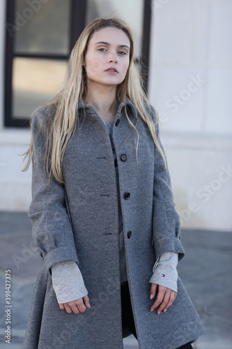  blond model girl in coat close up portrait on on city architecture background