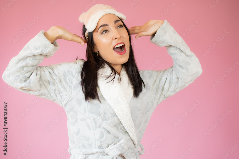 Relaxed joyful woman stretches hands after awakening, rejoices good day, enjoys pleasant sleep, wearing nightgown, has happy expression, poses over pink wall Relaxed joyful woman stretches hands after awakening, rejoices good day, enjoys pleasant sleep, wearing nightgown, has happy expression, poses over pink wall