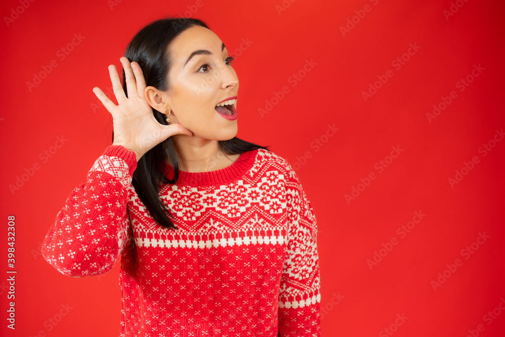 Young woman wearing red sweater smiling with hand over ear listening an hearing to rumor or gossip. Deafness concept. Young woman wearing red sweater smiling with hand over ear listening an hearing to rumor or gossip. Deafness concept.