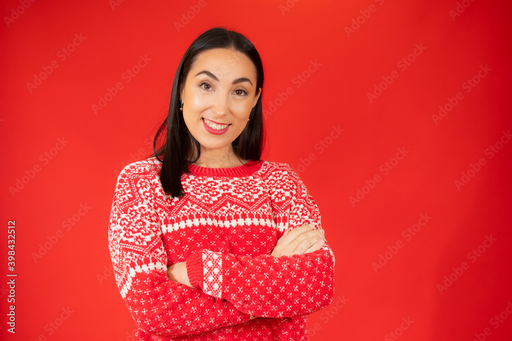 Portrait of a cheerful smiling woman in sweater standing with arms folded isolated on the red background Portrait of a cheerful smiling woman in sweater standing with arms folded isolated on the red background