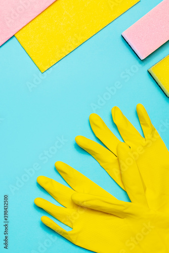 Microfiber, sponge and kitchen latex gloves on a blue background, top view. Cleaning supplies.