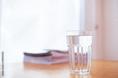 Purity drinking water in a drinking glass on the wooden table in office close up with copyspace. 
