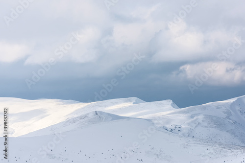 Snow-covered mountain range under a cloudy sky.