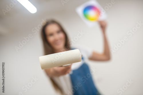 Young woman holding a color palette and a paint roller