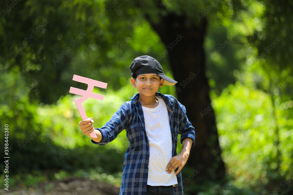 Cute indian little child holding indian rupees symbol in hand and showing expression