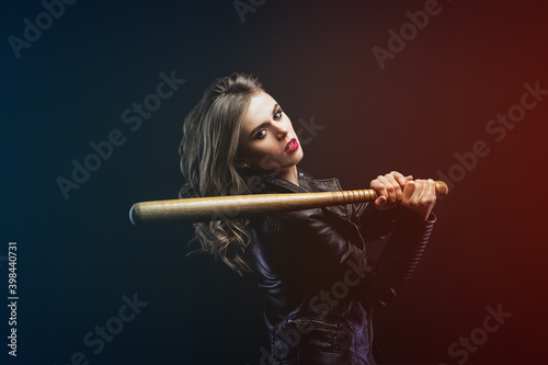 Portrait of young blonde beautiful woman in a leather jacket with wooden baseball bat Looks into the camera