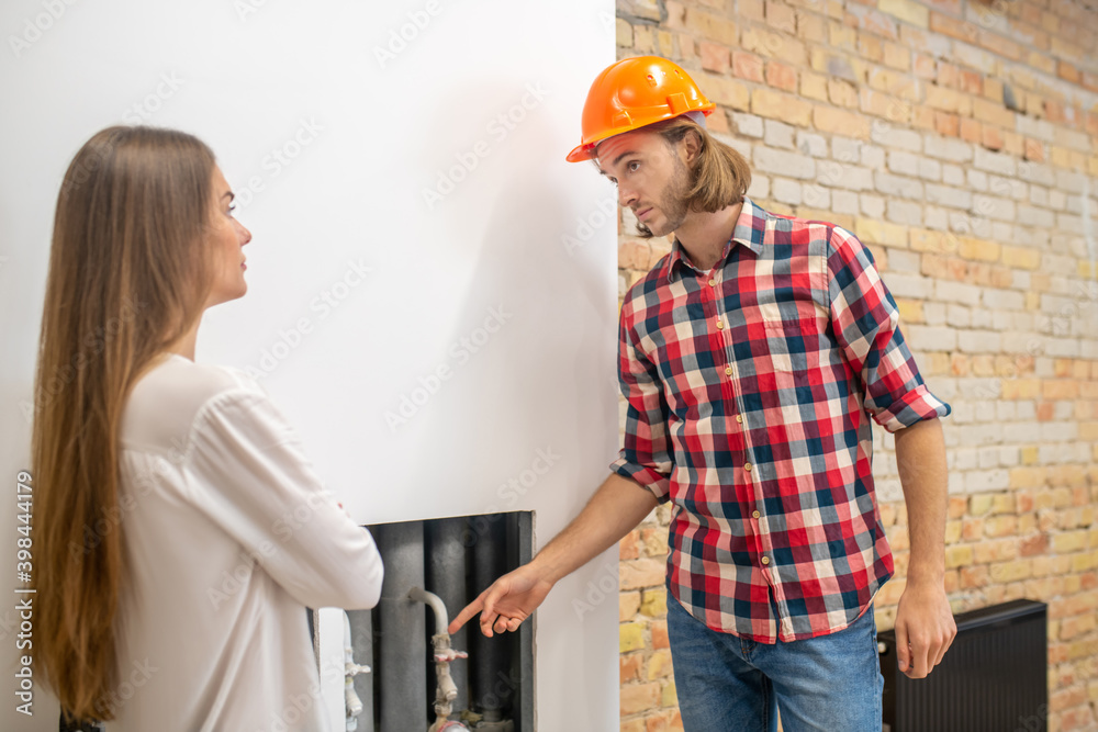 Construction worker in orange helmet explaining something to a customer Construction worker in orange helmet explaining something to a customer