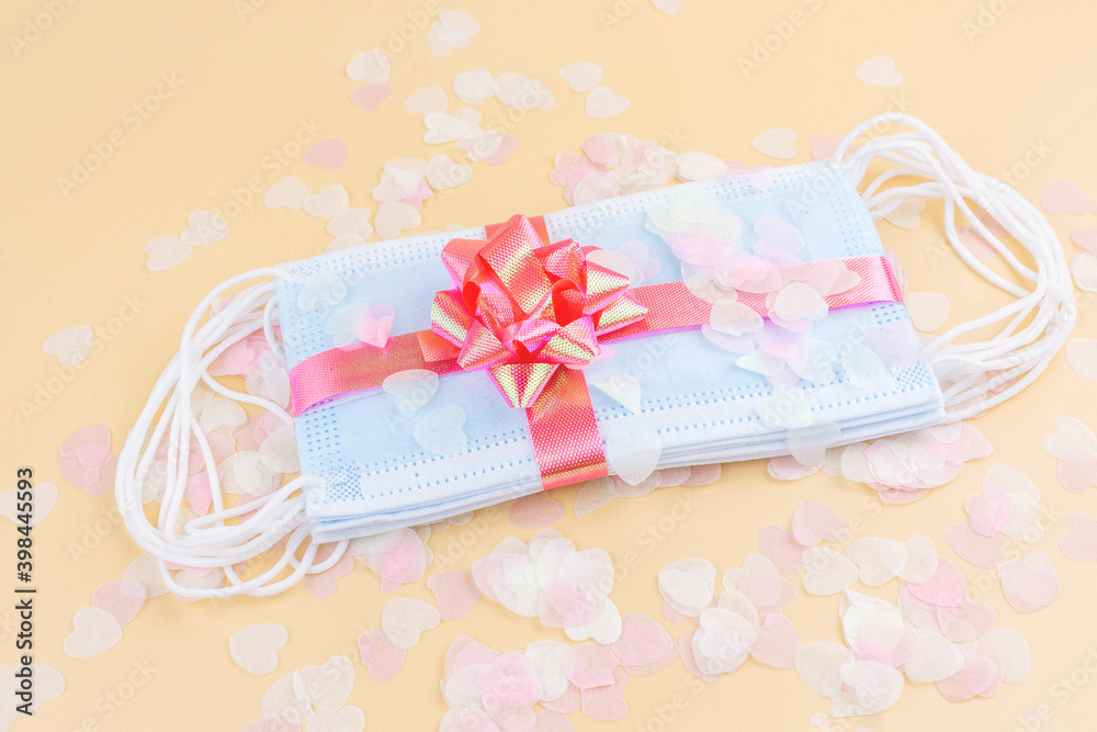 Medical protective masks with pink bow and confetti isolated on pastel background. Flat lay. Gift for holiday, birthday, Mother's Day, Valentine's day, Women's Day during coronavirus pandemic. Medical protective masks with pink bow and confetti isolated on pastel background. Flat lay. Gift for holiday, birthday, Mother's Day, Valentine's day, Women's Day during coronavirus pandemic.