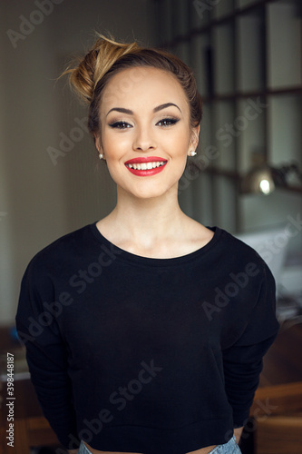 Front portrait of a beautiful blonde girl with hairstyle and makeup, indoors photo.