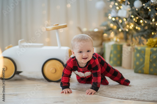 small baby sit under chrismas tree with light and presents smile