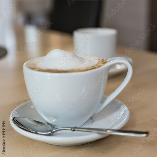 cappuccino in white cup and saucer on wooden table