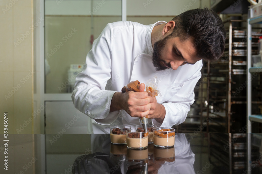 Closeup of pastry chef working finishing a dessert in glass. Closeup of pastry chef working finishing a dessert in glass.