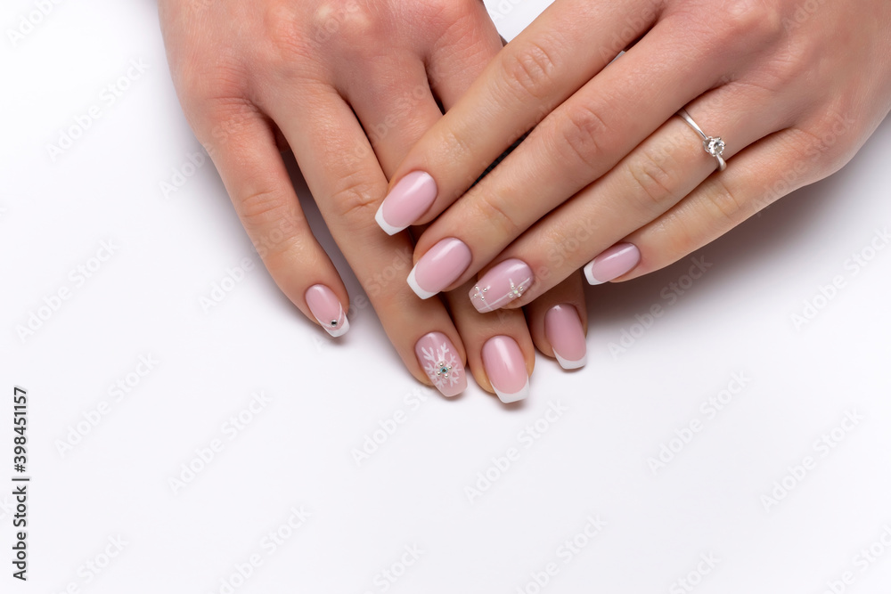 New Year's white French manicure on long square nails with snowflakes, crystals, rolls, close-up on a white background. New Year's white French manicure on long square nails with snowflakes, crystals, rolls, close-up on a white background.