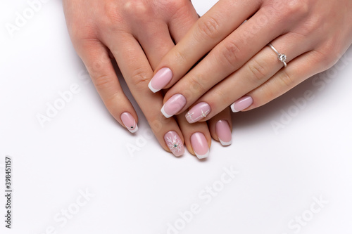 New Year's white French manicure on long square nails with snowflakes, crystals, rolls, close-up on a white background.
