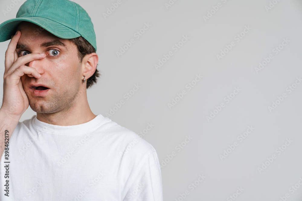 Young shocked man in cap expressing surprise on camera