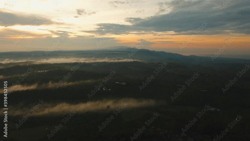 Aerial view of mystical, foggy forest forest, mountains with fog, clouds at sunset on Bali,Indonesia. Tropical rainforest, trees, jungle in mountains. Fog over the jungle. Travel concept. Aerial Aerial view of mystical, foggy forest forest, mountains with fog, clouds at sunset on Bali,Indonesia. Tropical rainforest, trees, jungle in mountains. Fog over the jungle. Travel concept. Aerial
