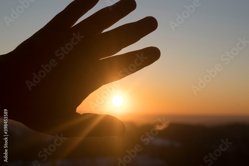 man's hand reaches out to the setting sun, the concept of hope, desire, dreams.. Conceptual design.