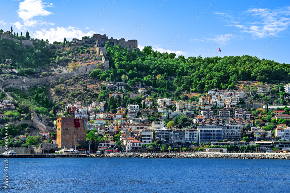 Kizil Kule Tower and Alanya Old Town on the hillside - view from the sea. Panorama of Turkish tourist town on a summer sunny day