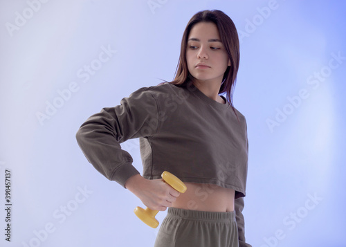girl with dumbbells on a blue background doing sports exercises