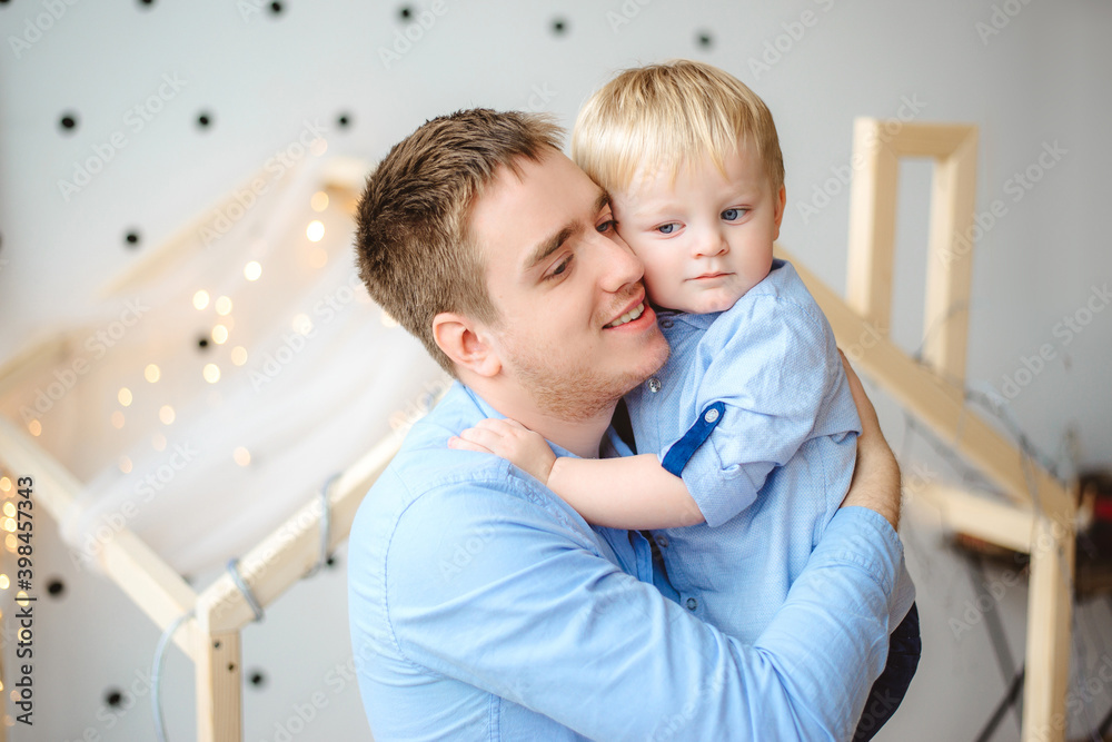 Dad and 3-year-old son play at home. Father's holding the boy in his arms. The man and the child are happy and smile. Dad and 3-year-old son play at home. Father's holding the boy in his arms. The man and the child are happy and smile.