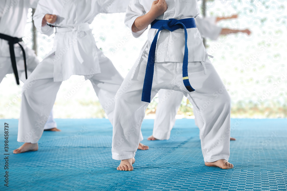 Children in kimono practicing karate on tatami outdoors, closeup