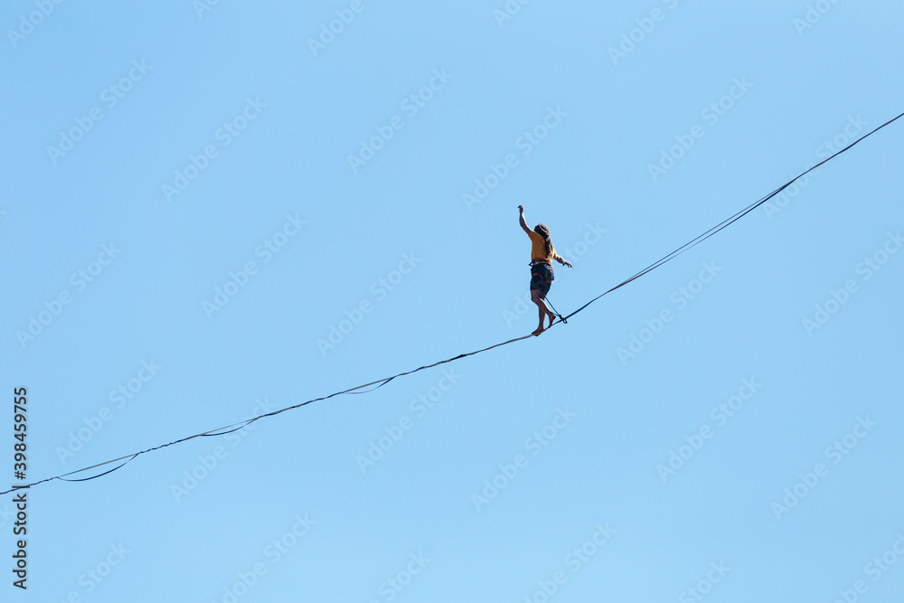 A man walks along the highline against the blue sky. A man walks along the highline against the blue sky.