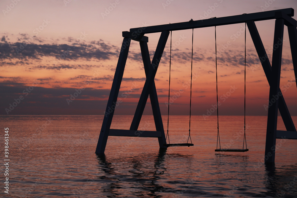 Fototapeta premium Picturesque view of swing in water on sunrise