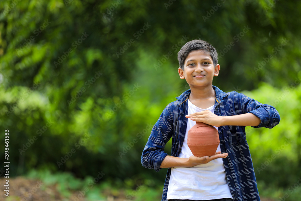Cute indian child holding clay piggy bank in hand Cute indian child holding clay piggy bank in hand