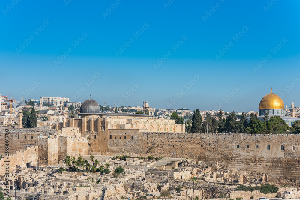 Dome of Al-Aqsa Mosque and golden dome of the Rock, built on top of the Temple Mount, known as Haram esh-Sharif in Islam and wall of old city of Jerusalem, Israel. View from Mount of Olives.