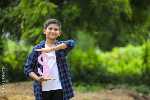 Cute indian little child holding dollar Sign on nature Background