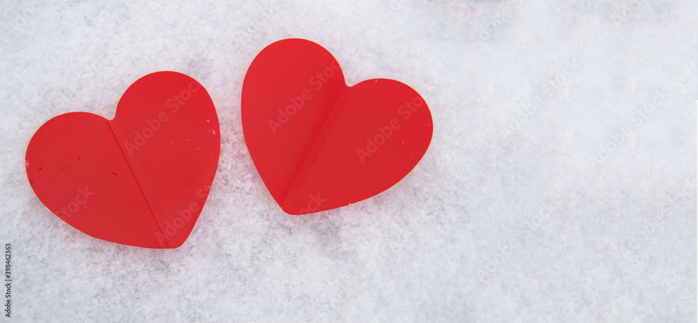Two beautiful romantic red hearts together on a white snowy background. The concept of love and Valentine's Day Two beautiful romantic red hearts together on a white snowy background. The concept of love and Valentine's Day