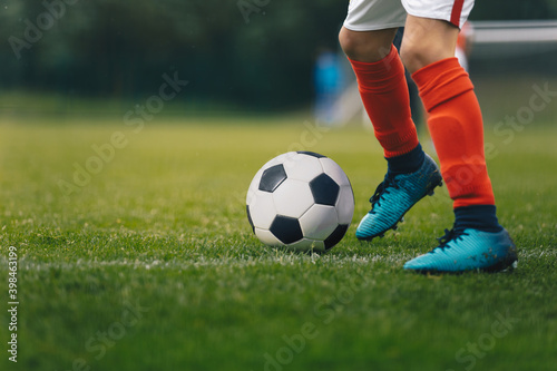Soccer Players Legs. Footballer Kicking Ball on Natural Grass Field. Closeup Image of Soccer Boy in Cleats and Soccer Socks Running Ball © matimix