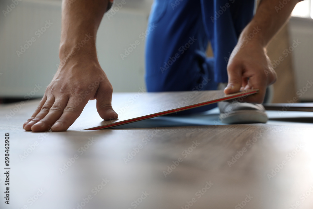 Worker installing laminated wooden floor indoors, closeup Worker installing laminated wooden floor indoors, closeup