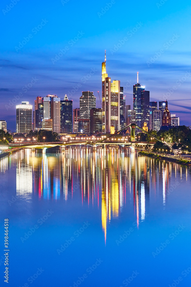 Nicely illuminated skyline of Frankfurt, Germany, in the evening with reflections on the river Main