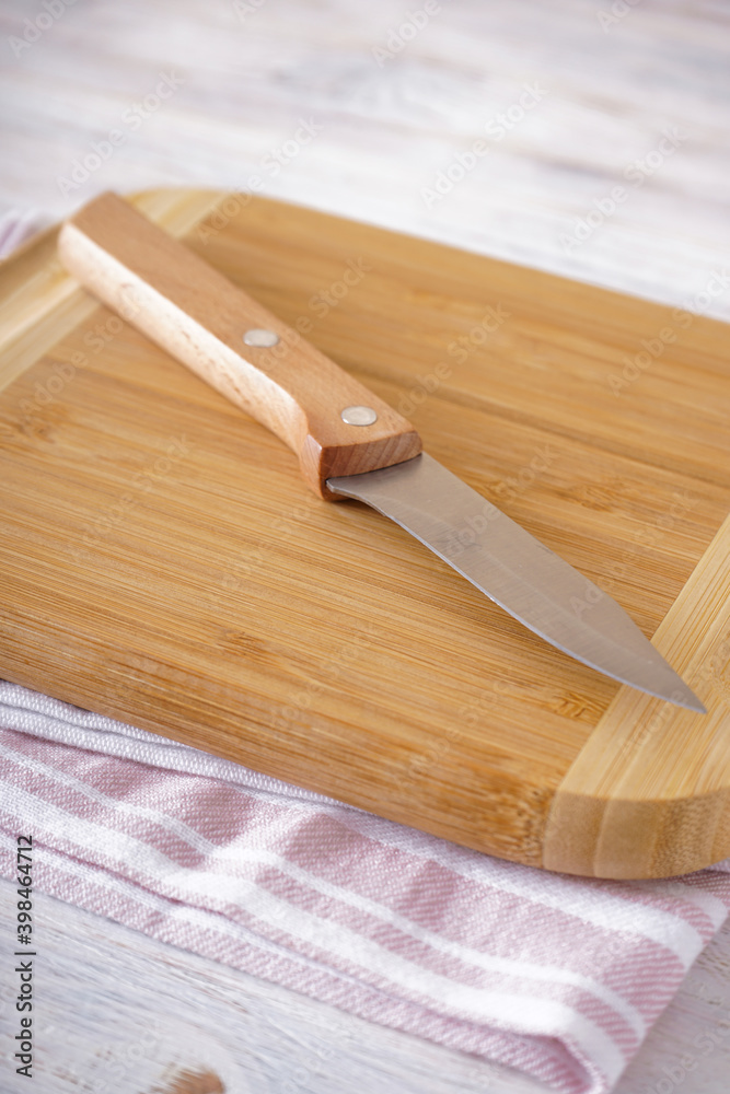 Wooden cutting board and knife on a wooden background, close-up. Vertical