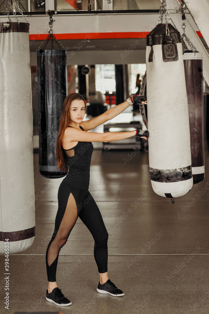 Fit woman and punching bag during training in the gym