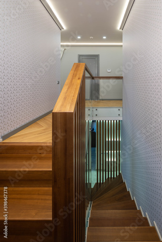 Contemporary interior of hall in private house. Wooden floor  staircase and handrails.