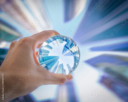 Woman's hand holding the glass ball  with skyscrapers reflection. Moscow International Business Center reflection in the transparent glass sphere look up   