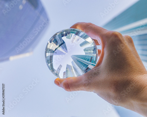 Woman's hand holding the glass ball  with skyscrapers reflection. Moscow International Business Center reflection in the transparent glass sphere look up   