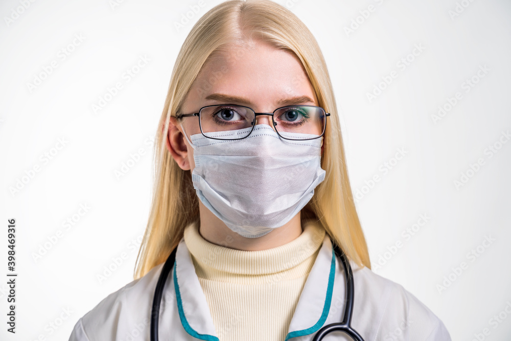 Head and shoulders portrait of female doctor wearing protective mask and looking at camera posing against white background Head and shoulders portrait of female doctor wearing protective mask and looking at camera posing against white background