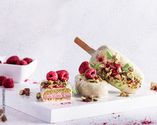 Ice cream sticks with white chocolate, fruit, pistachios and colored sugar on a white background.