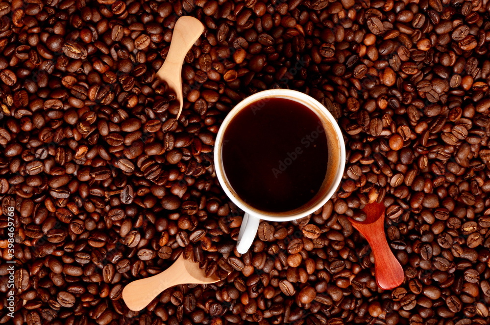 Naklejka premium Coffee beans background with small wooden spoons