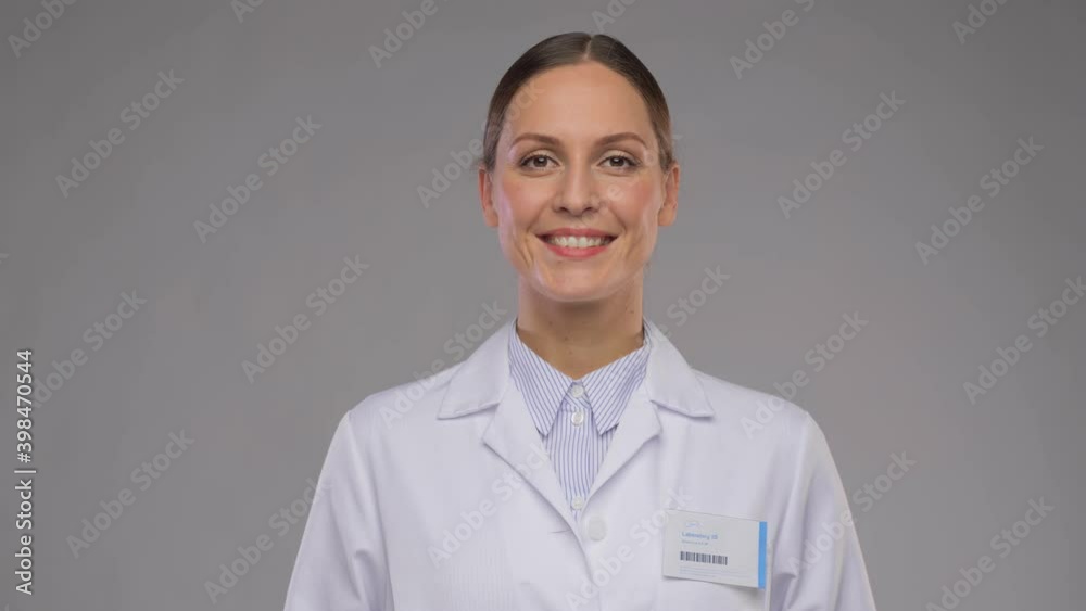 medicine, profession and healthcare concept - happy smiling female doctor or scientist in white coat with badge over grey background medicine, profession and healthcare concept - happy smiling female doctor or scientist in white coat with badge over grey background