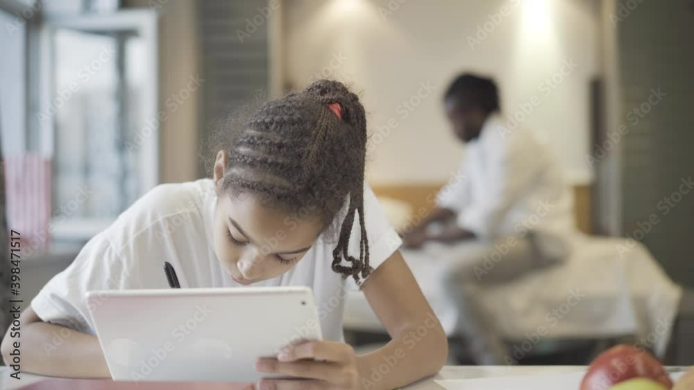 Concentrated African American teenage girl doing homework at home with ...